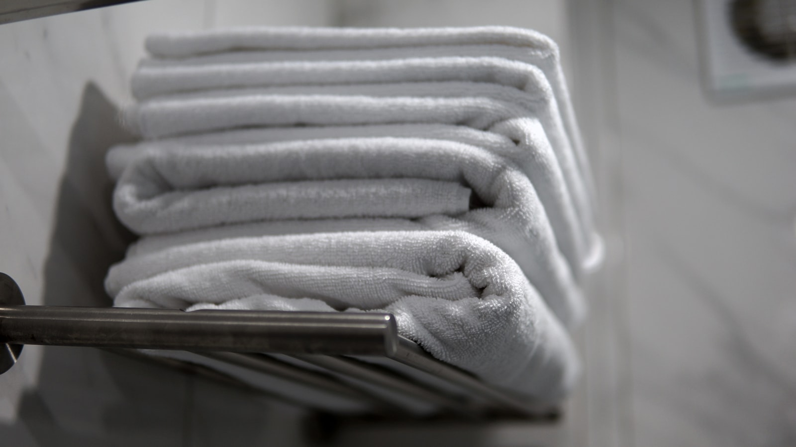 A stack of clean folded towels on a rack, representing a well-prepared massage session