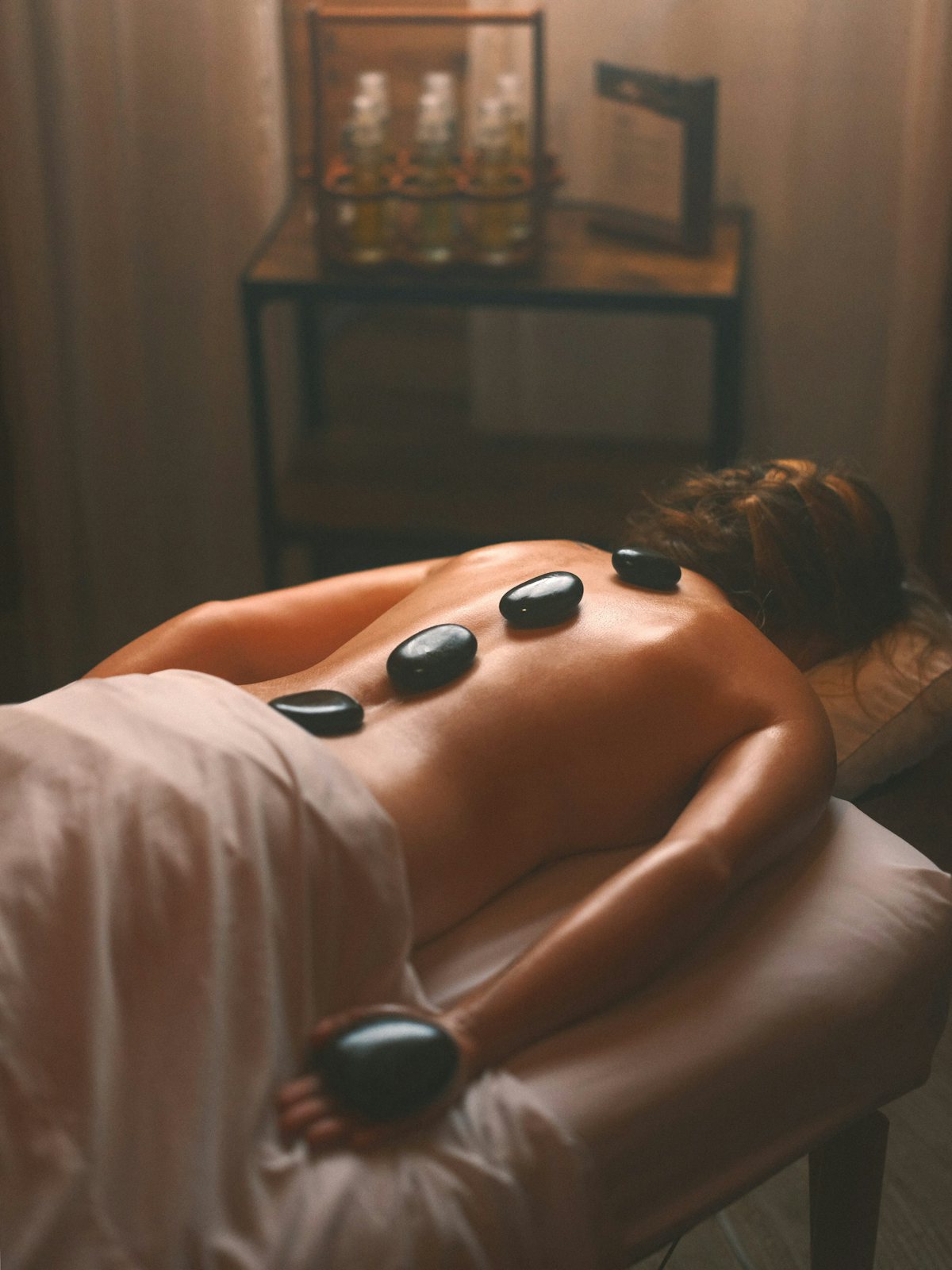 Hot stone massage technique being performed on a client's back at a spa